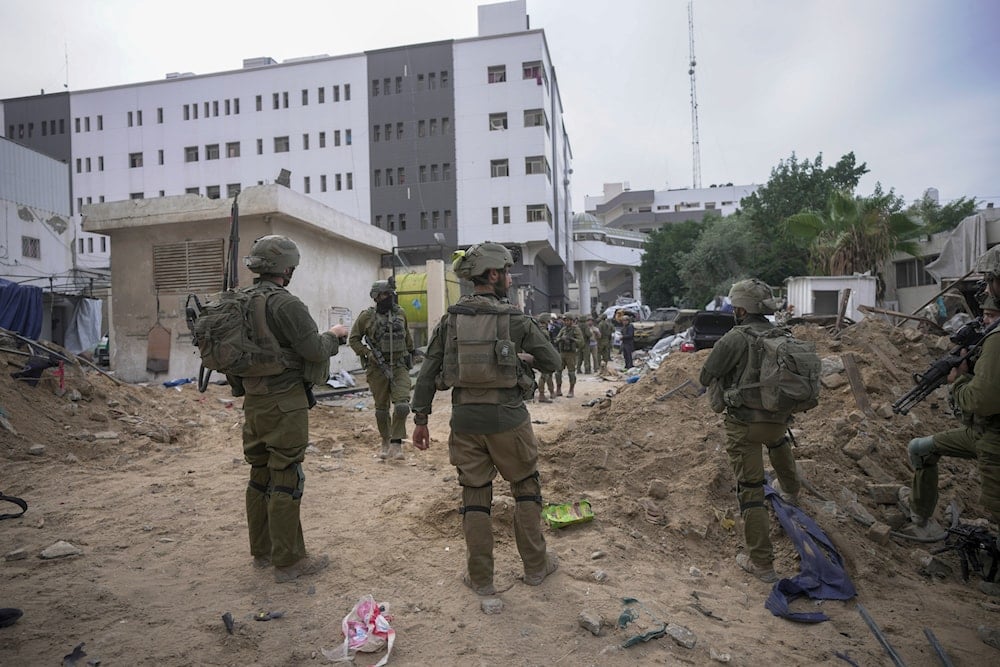 Israeli occupation soldiers stand outside Shifa Hospital in Gaza City, occupied Palestine, November 22, 2023 (AP)