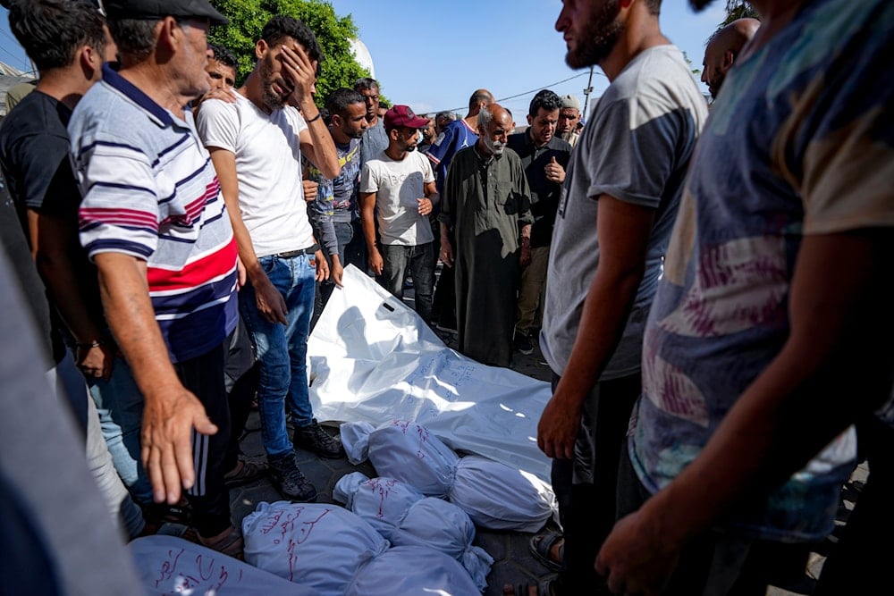 Palestinians gather near the bodies of their relatives killed in the Israeli bombardment of the Gaza Strip, at a hospital in Deir al-Balah, July 18, 2024 (AP)