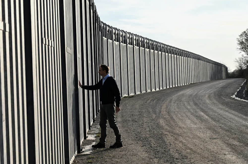 Greek prime minister Kyriakos Mitsotakis walks next to the steel fence during a ceremony marking the signing of the extension to the country's steel fence on the border with Turkey. (AFP)