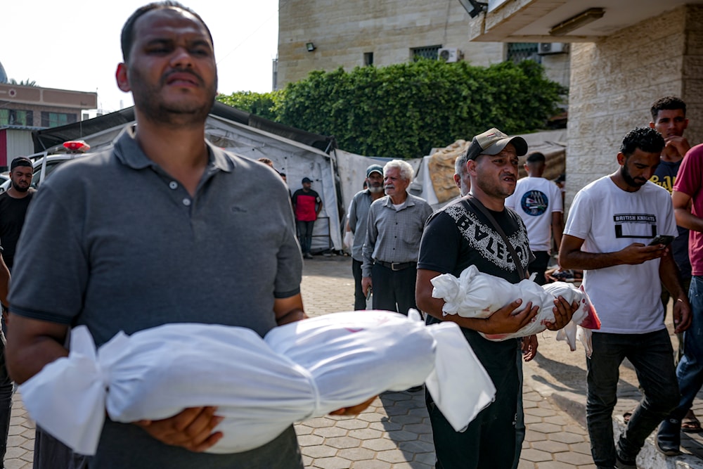 Palestinians hold the bodies of their relatives killed in the Israeli bombardment of the Gaza Strip, at a hospital in Deir al-Balah, Sunday, July 21, 2024. (AP)