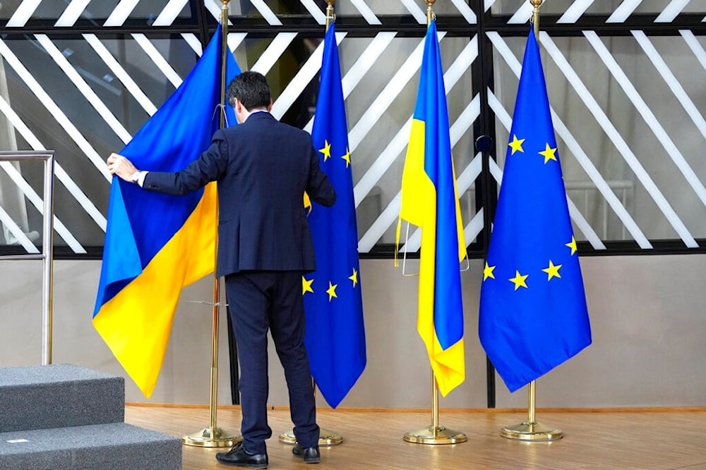 A member of protocol arranges the Ukrainian and EU flags during an EU summit at the European Council building in Brussels on Thursday, Feb. 9, 2023. (AP)