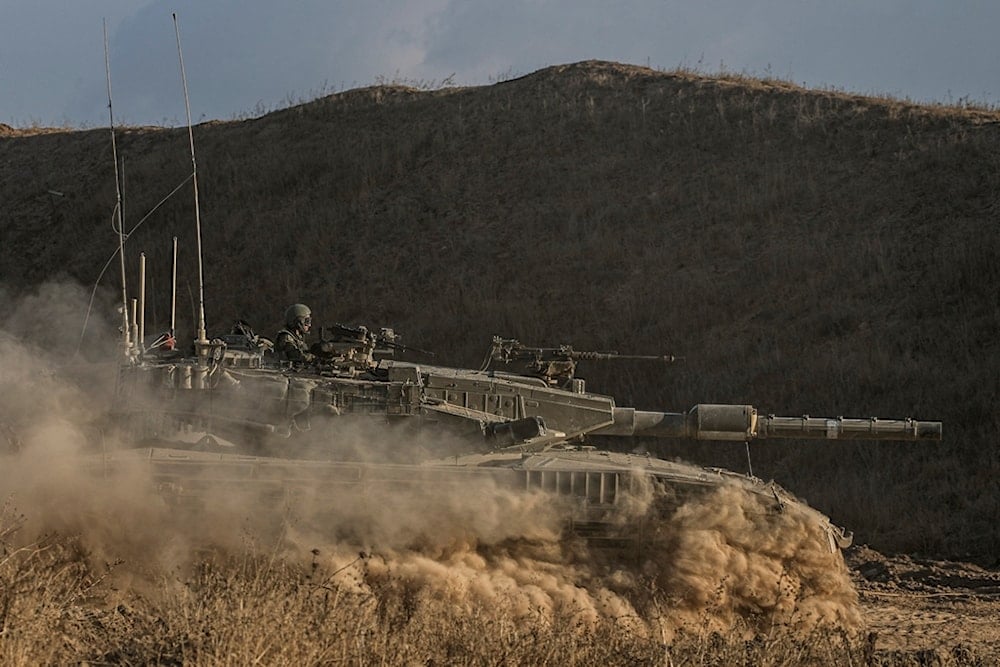 An Israeli soldier moves on the top of a tank near the Israeli-Gaza border, as seen from southern Israel, Sunday, July 14, 2024. (AP Photo/Tsafrir Abayov)