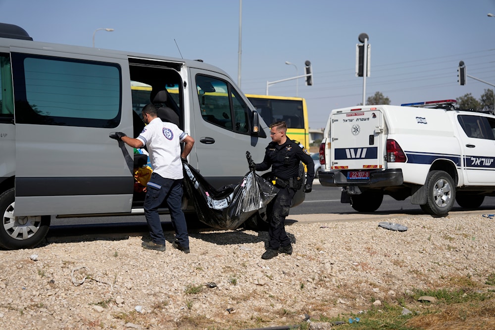 An Israeli occupation Police officer and paramedic remove a body found on June 13, 2024, in southern occupied Palestine (AP)