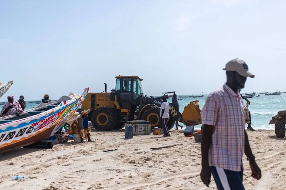 An earth-moving machine transporting bodies of migrants who perished in a shipwreck off the coast of Mauritania drives away on a beach outside Nouakchott on July 24, 2024. (AFP)