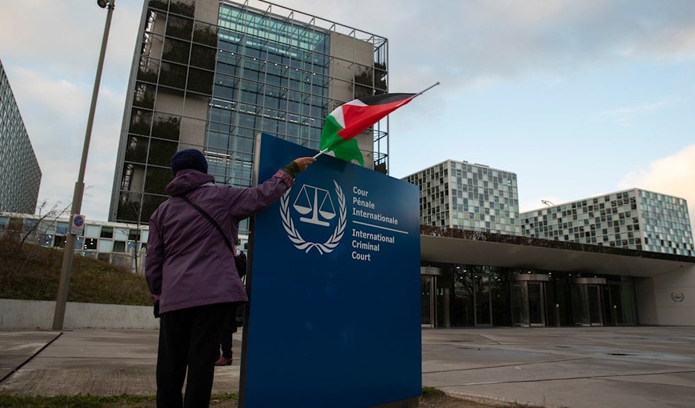 A demonstrator poses with a Palestinian flag outside the International Criminal Court during a rally urging the court to prosecute 