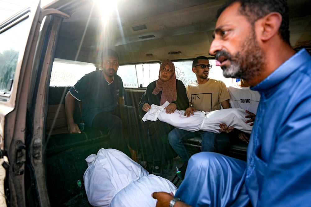 Palestinians hold the bodies of their relatives killed in the Israeli bombardment of the Gaza Strip, at a hospital morgue in Deir al-Balah, July 16, 2024 (AP)