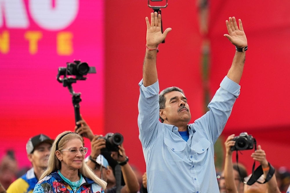 President Nicolas Maduro, accompanied by first lady Cilia Flores, raises his arms during his closing election campaign rally in Caracas, Venezuela, Thursday, July 25, 2024. Maduro is seeking a third term in the July 28 vote. (AP)