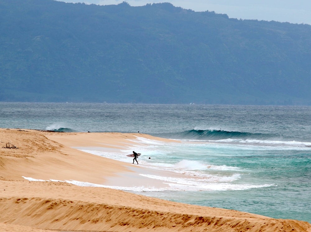 A surfer walks out of the ocean on Oahu's North Shore near Haleiwa, Hawaii, March 31, 2020 (AP)