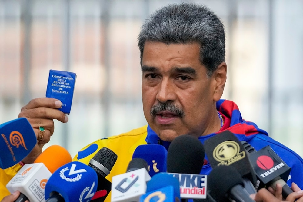 President Nicolas Maduro displays a mini edition of Venezuela's constitution after voting in the presidential elections in Caracas, Venezuela, Sunday, July 28, 2024. (AP)