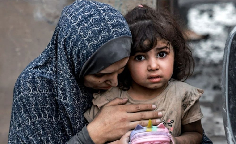 A Palestinian mother with her daughter sits near destroyed houses following airstrike in Rafah on the southern Gaza strip on November 6,2023. (AFP via Getty Images)