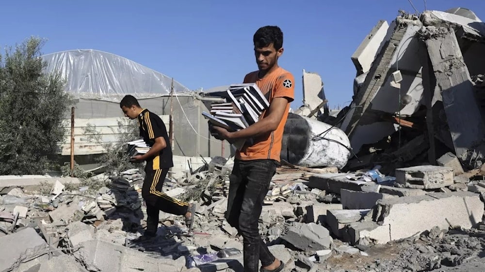 Palestinians collect books from the rubble of a cultural center after an Israeli strike in Rafah on 18 November (AFP)