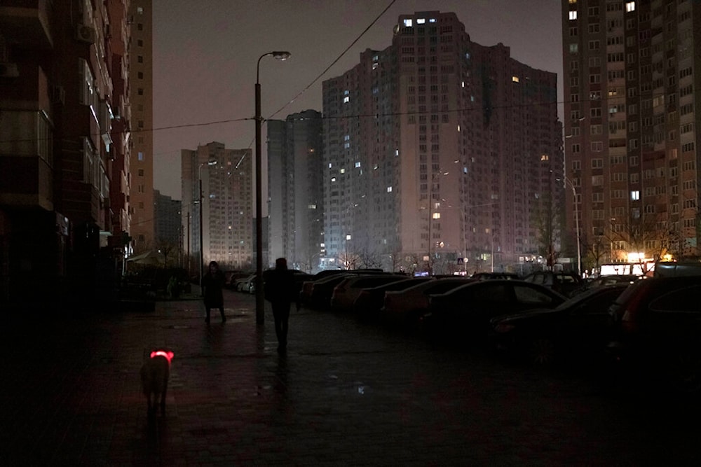 A dog with a lit up collar walks in a street during a blackout in Kiev, Ukraine, Wednesday, Nov. 16, 2022. 