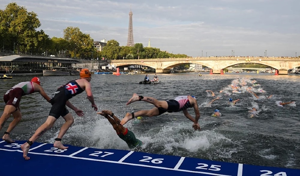 Triathlon athletes dive in the Seine River during the men's 2023 World Triathlon Olympic Games test event in Paris on August 18, 2023. (AFP)