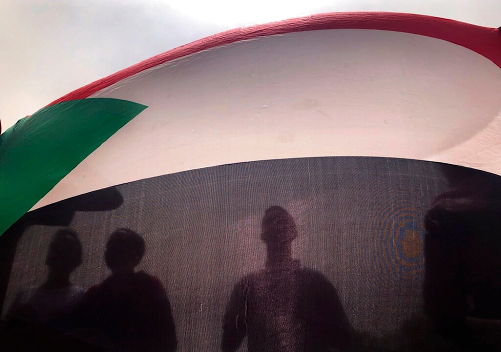 In this June 30, 2019 file photo, Sudanese protesters hold their national flag as they march during a demonstration, in Khartoum, Sudan. (AP)