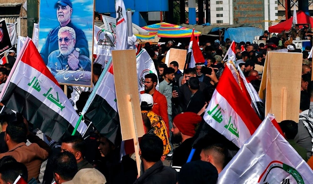 Supporters of the Popular Mobilization Forces hold a poster of Abu Mahdi al-Muhandis, and General Qassem Soleimani during a protest, in Tahrir Square, Iraq, Sunday, Jan. 3, 2021. (AP)