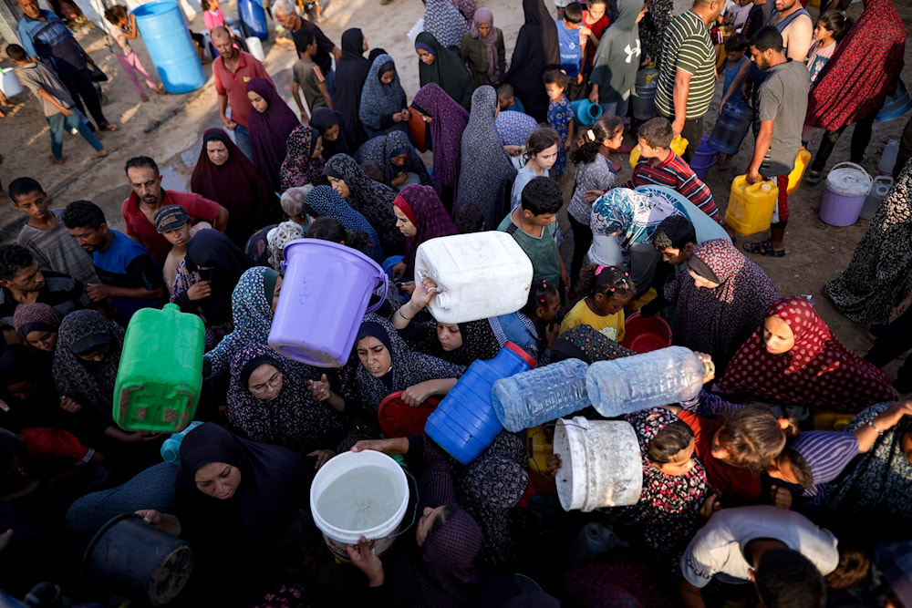 Palestinians displaced by the Israeli bombardment of the Gaza Strip queue for water at a makeshift tent camp in the southern town of Khan Younis, Monday, July 1, 2024. (AP)