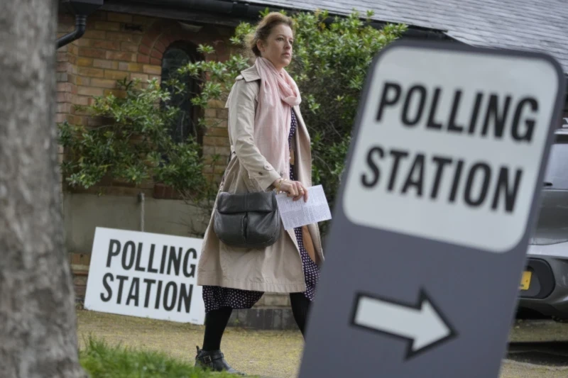 Woman holds voting card as she arrives to a vote in London in local elections, May 2, 2024. (AP)