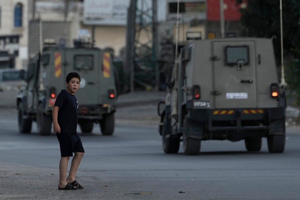 A Palestinian boy watches as Israeli forces' armored vehicles move through the Balata refugee camp in the West Bank city of Nablus, occupied Palestine, June 3, 2024. (AP)