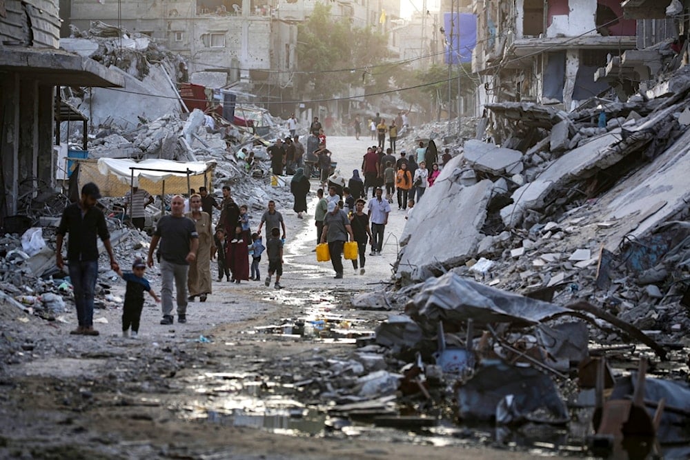 Palestinians displaced by the Israeli air and ground offensive on the Gaza Strip, walk through a dark streak of sewage flowing into the streets of the southern town of Khan Younis, Gaza Strip, Thursday, July 4, 2024. (AP)