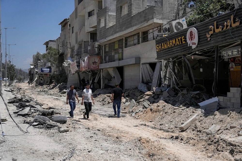 Palestinians walk along a damaged road following an Israeli occupation forces operation in Nur Shams refugee camp, near the West Bank town of Tulkarm, Palestine, July 1, 2024. (AP)