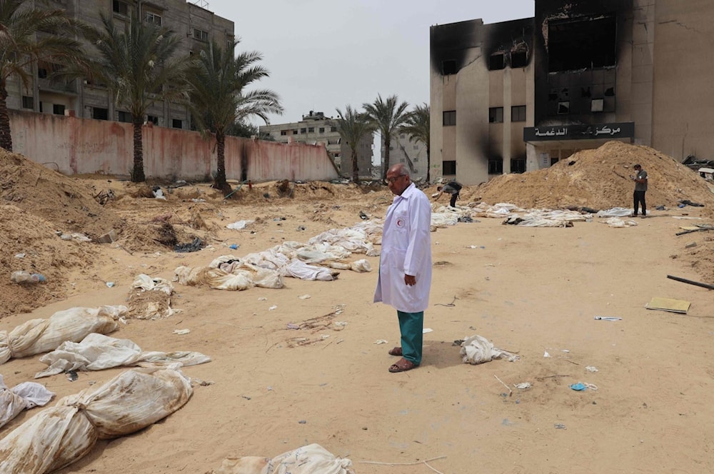 A doctor stands near bodies lined up for identification after they were unearthed from a mass grave found in the Nasser Medical Complex, southern Gaza Strip, Palestine, April 25, 2024. (AFP)