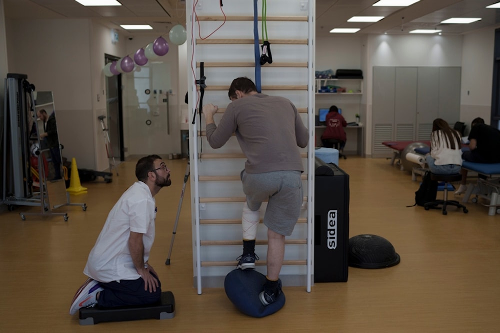 A physiotherapist assists Israeli soldier during his treatment session at the new Gandel Rehabilitation Center of the Hadassah hospital, in occupied al-Quds, Palestine, Wednesday, Feb. 21, 2024. (AP)