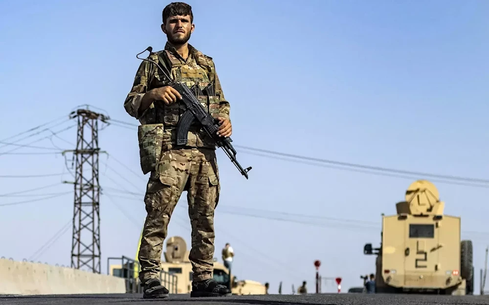 A Syrian Democratic Forces member stands guard along a road in town of al-Busayrah in Syria's Deir Ezzor province, on 4 September 2023 (AFP)