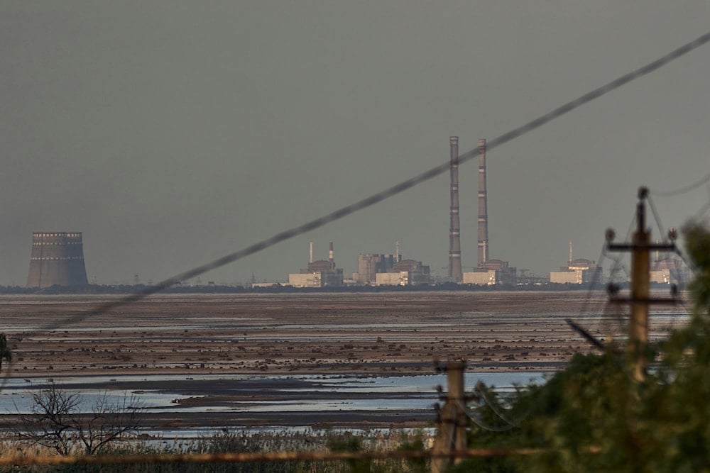 The Zaporozhye nuclear power plant, Europe's largest, is seen in the background of the shallow Kakhovka Reservoir after the dam collapse, in Energodar, June 27, 2023 (AP)