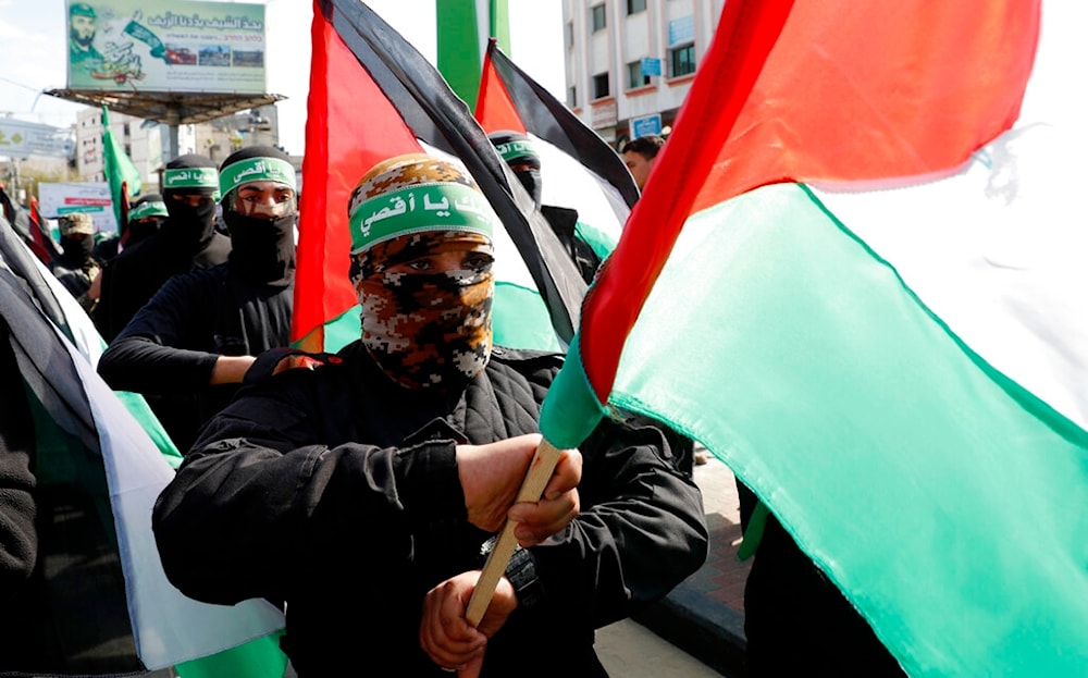 In this Feb. 21, 2020, file photo, masked Hamas fighters wave their national flags during a protest in Gaza City. (AP)