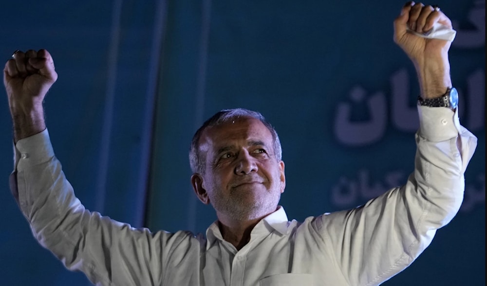 Iranian President Masoud Pezeshkian raises his fists during a campaign rally in Tehran, July 3, 2024. (AP)