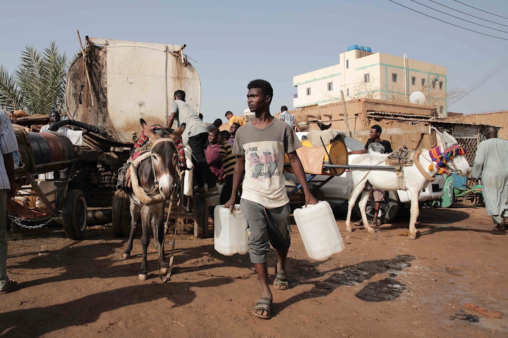 People gather to collect water in Khartoum, Sudan, on May 28, 2023, during a weeklong truce, brokered by the US and the Saudis (AP)