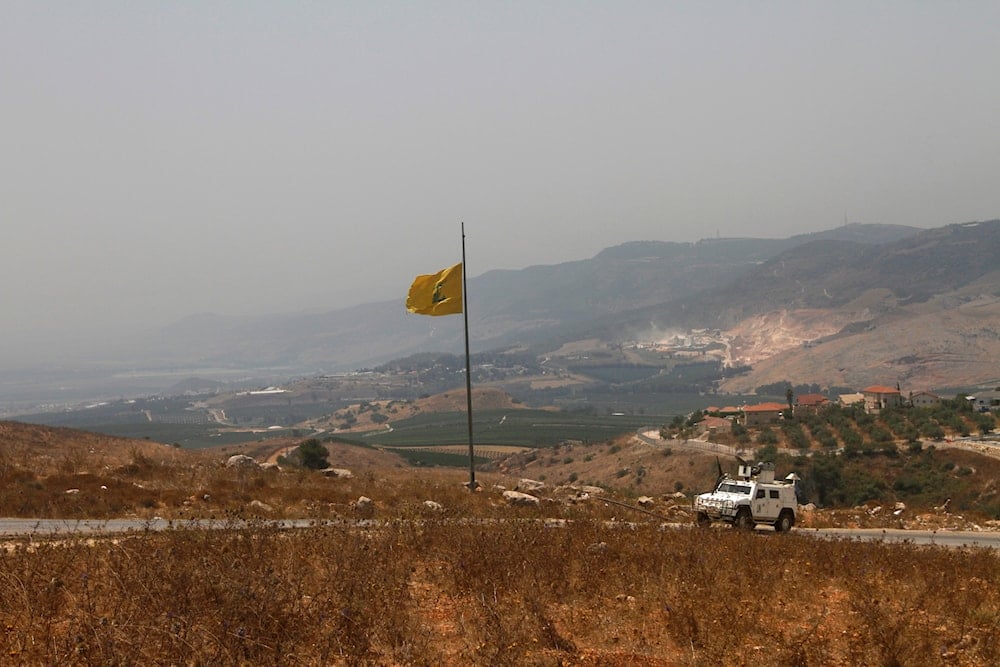 A UN vehicle patrols near a Hezbollah flag at the border in the southern village of Kfar Kila, in southeast Lebanon, July 28, 2020 (AP)