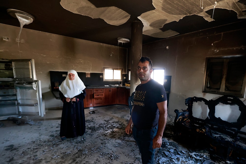 A Palestinian family stands inside their damaged home, a day after an attack by Israeli settlers on the village of Jit near Nablus in the West Bank killing a 23-year-old man dead and others with critical gunshot wounds, on August 16, 2024. (AFP)