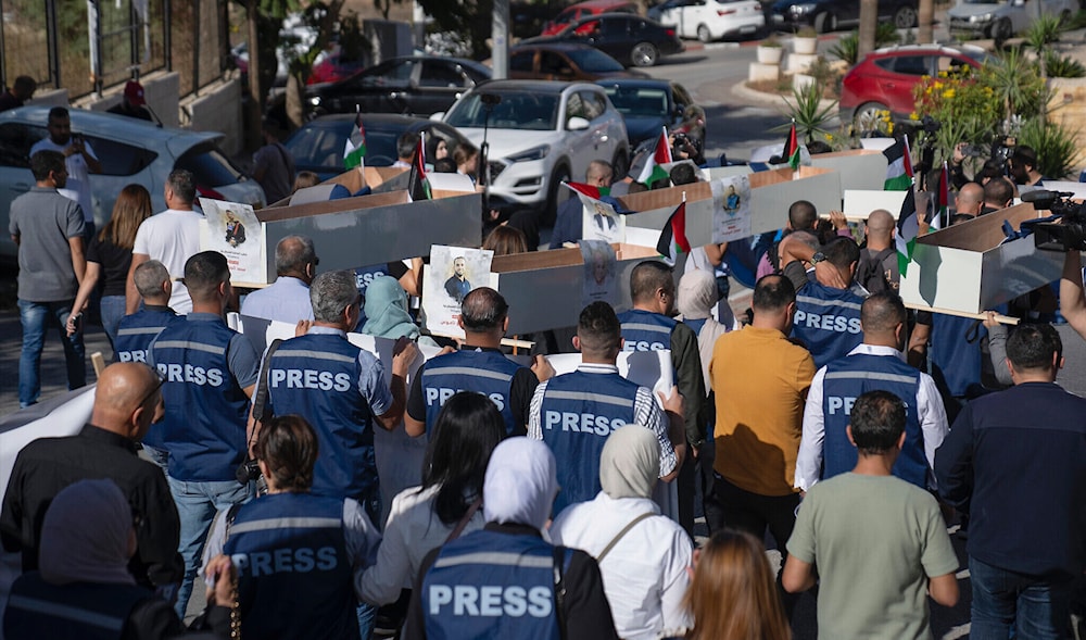 Palestinian journalists carry mock coffins of Palestinian journalists who were killed during the current war in Gaza during a symbolic funeral toward a United Nations office, in the West Bank city of Ramallah, on November 7, 2023. (AP)