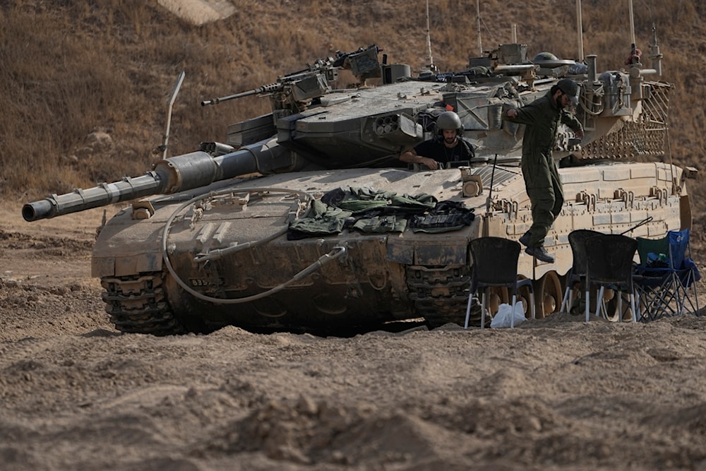 An Israeli occupation soldier jumps from the top of a tank in an area near the Israeli-Gaza border, Wednesday, July 24, 2024. (AP)