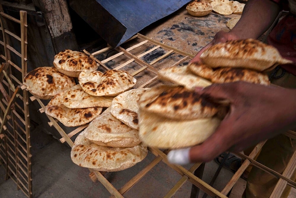 A worker collects Egyptian traditional 'baladi' flatbread, at a bakery, in el-Sharabia, Shubra district, Cairo, Egypt, Wednesday, March 2, 2022. (AP)