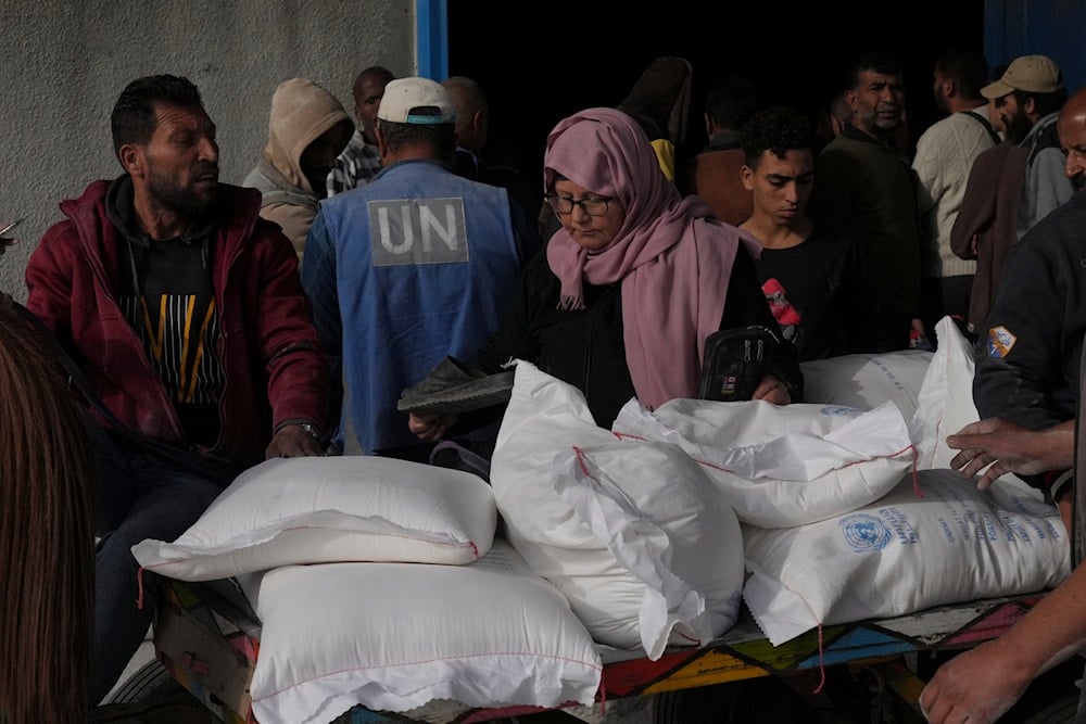 Palestinians take wheat from a UN distribution center in the al-Bureij refugee camp in the Gaza Strip on December 10, 2023. (AP)