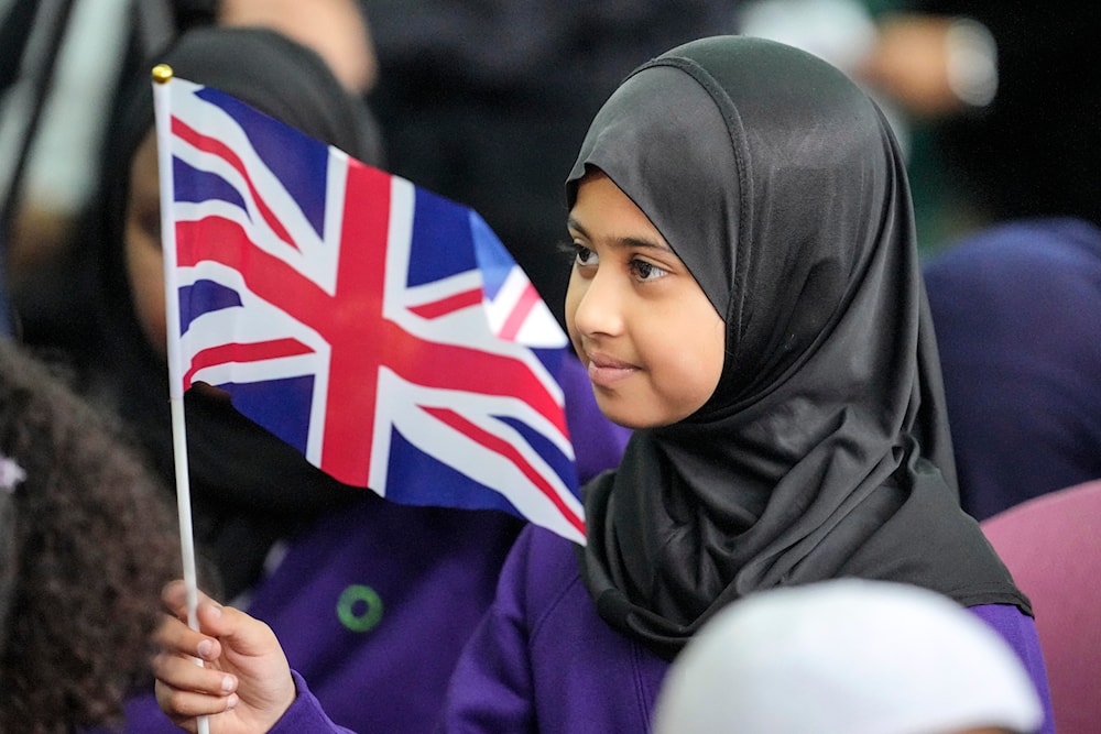 A girl from the Olive School waves a flag of the United Kingdom during a national Muslim memorial at the central mosque in London, England, Sept. 15, 2022. (AP)