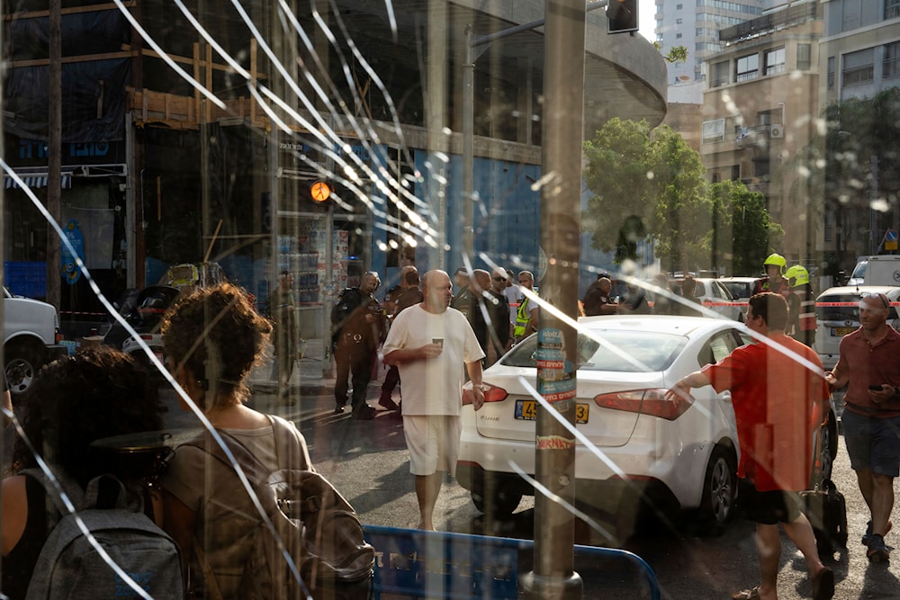 People are seen through a broken window next to the scene of an explosive drone attack in Tel Aviv, Israel, Friday, July 19, 2024. (AP)