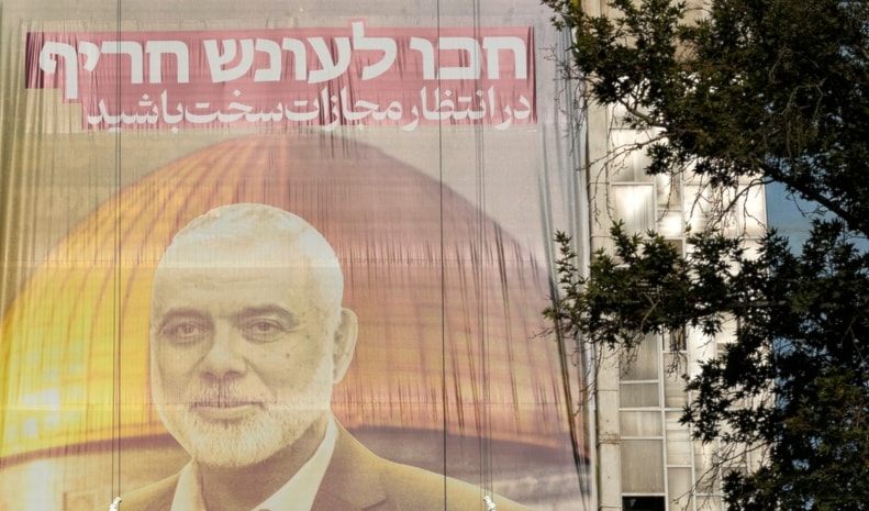 Iranian workers install a huge banner on a wall showing a portrait of Hamas leader Ismail Haniyeh with a sign which reads in Farsi and Hebrew: 