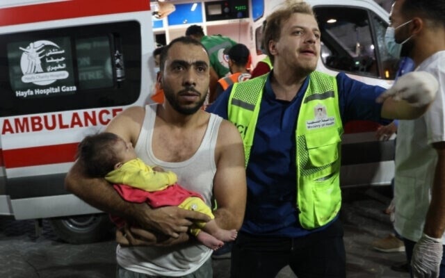 A man transports an injured Palestinian baby into al-Shifa hospital in Gaza following a brutal Israeli airstrike on October 11,2023. (AFP)