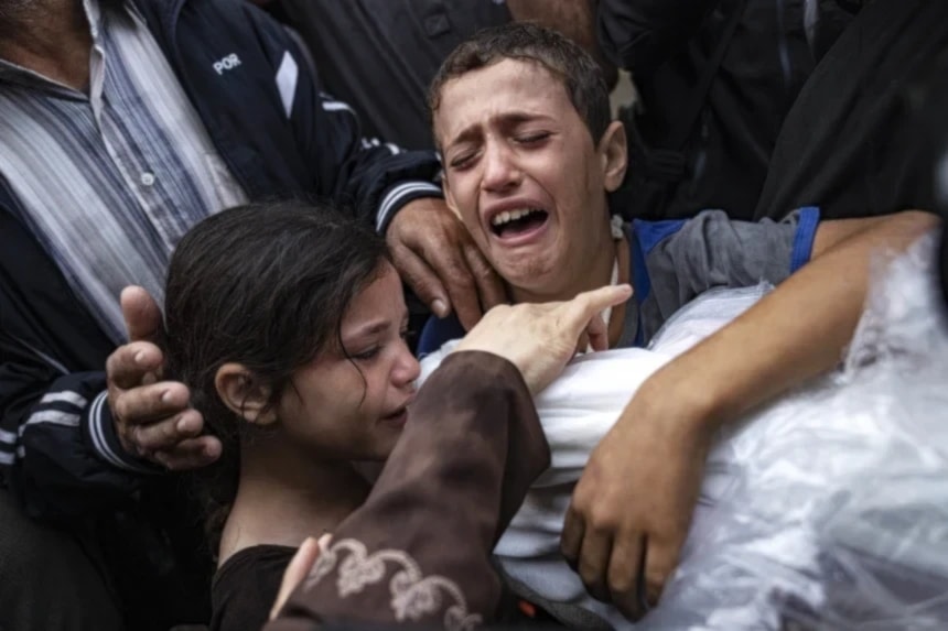 Palestinian children crying while holding the body of their mother who was killed in an Israeli airstrike on Gaza in November 2023 (AP)