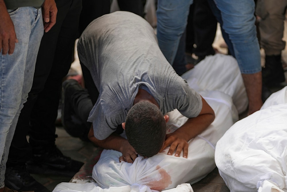 A Palestinian weeps over a body at the funeral for more than 15 people, including several children and women, killed in an Israeli strike, at Al-Aqsa Martyrs Hospital in Deir al-Balah, Gaza Strip, Saturday, Aug. 17, 2024. (AP)