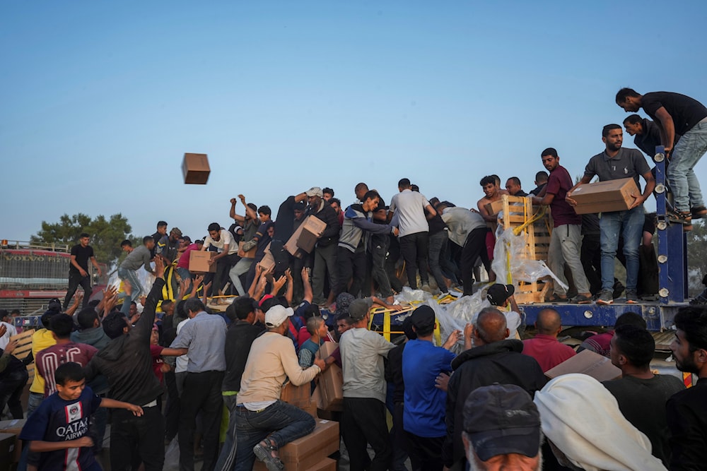 Palestinians are storming trucks loaded with humanitarian aid brought in through a new US-built pier, in the central Gaza Strip, Saturday, May 18, 2024 (AP)