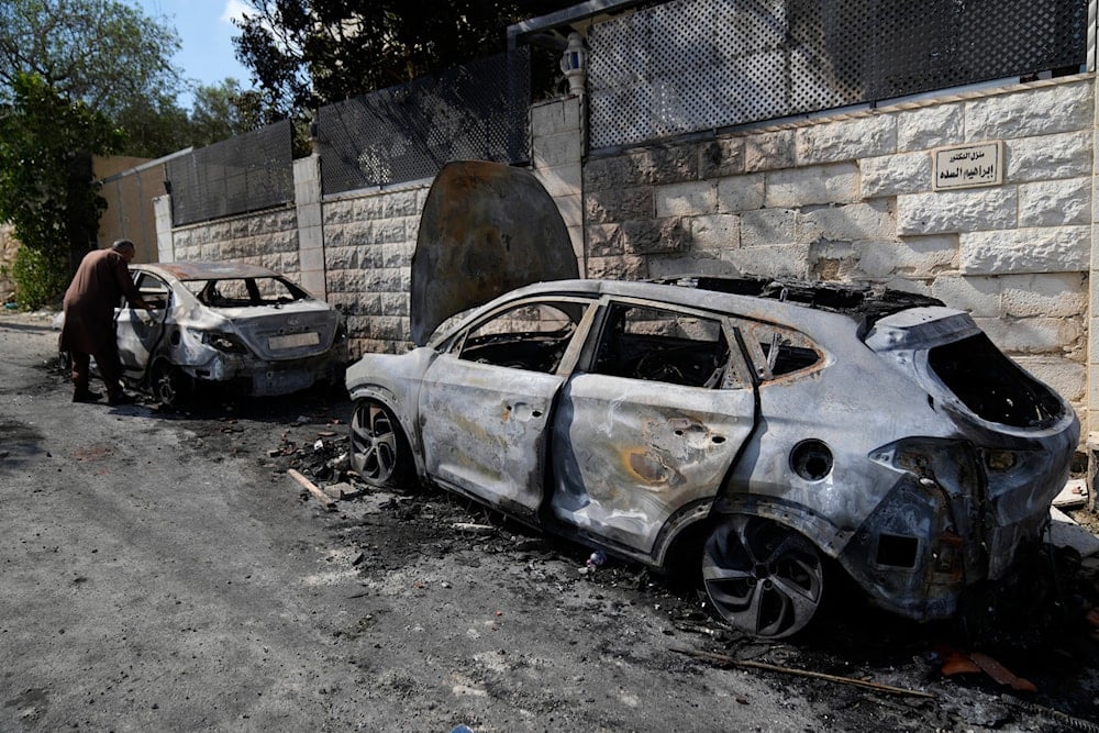 A Palestinian examines a torched vehicle, seen the morning after a rampage by Israeli settlers in the West Bank village of Jit, on August 16, 2024. (AP)