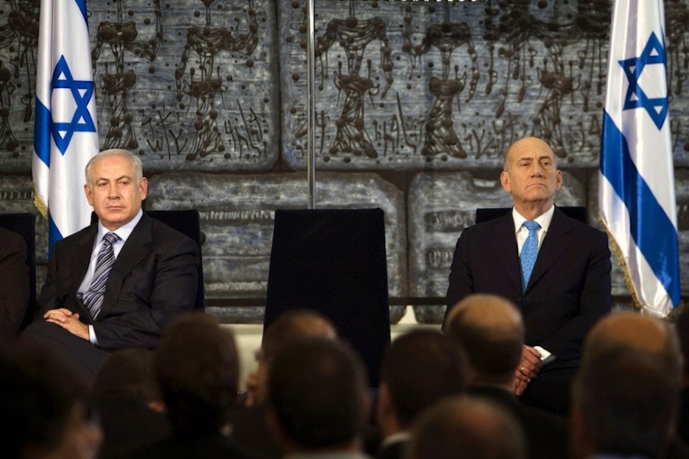 Then outgoing Israeli occupation Prime Minister Ehud Olmert, sits with now incumbent occupation PM Benjamin Netanyahu during a handover ceremony in al-Quds, occupied Palestine, April 1, 2009. (AP)