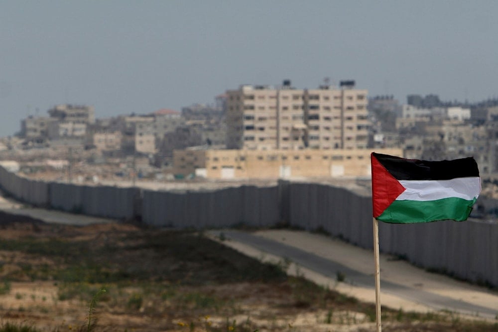 A Palestinian flag is seen with the background of a section of the wall in the Philadelphi corridor between Egypt and Gaza, on the background, near the southern Gaza Strip town of Rafah, Sunday, July 1, 2007. (AP)