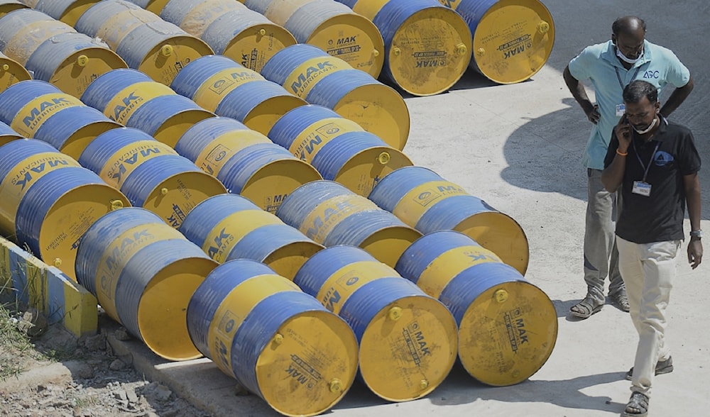 Workers walk past oil barrels at a filling station in Chennai, India on February 24, 2022. (AFP)