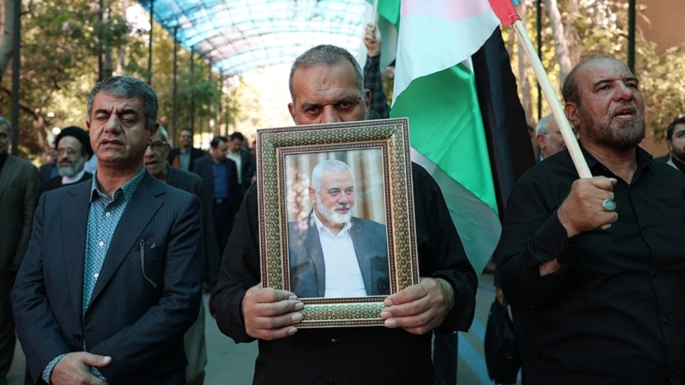 A man Raising a picture of the martyr Ismail Haniyeh, during his funeral in Tehran, on August 1, 2024 (Agencies)