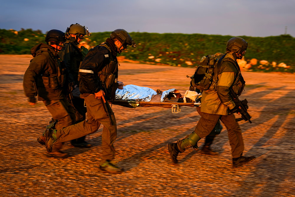 Israeli occupation force carry a stretcher towards a military helicopter during an exercise simulating evacuation of wounded soldiers in 'Israel', near the border with Lebanon, Feb. 20, 2024. (AP)